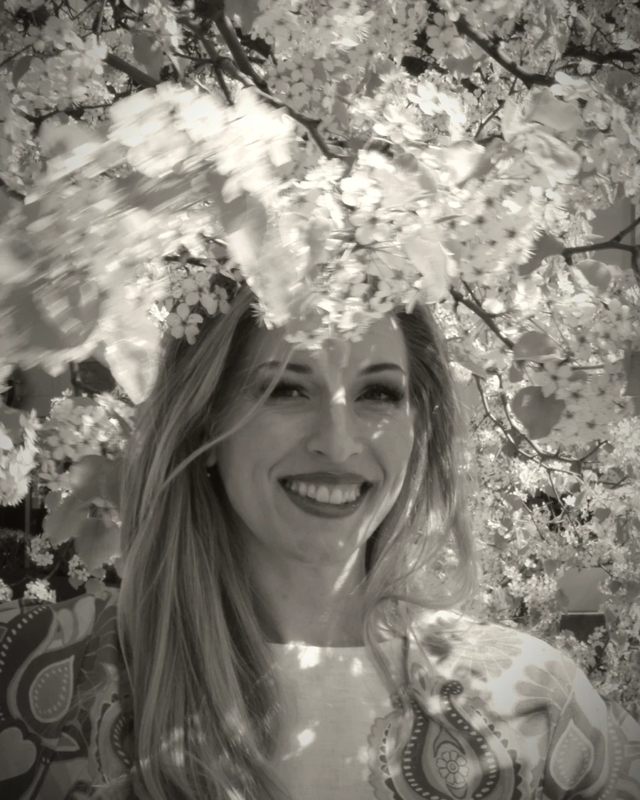 Cher, founder of Vega Botanica, beneath a tree in full white blossom